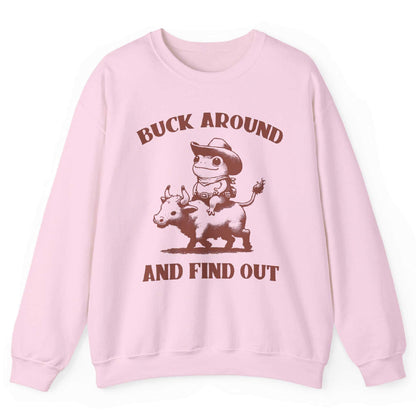 Light pink sweatshirt with cowboy frog riding bull and “Buck Around and Find Out” text – front view, by Shirtcasm