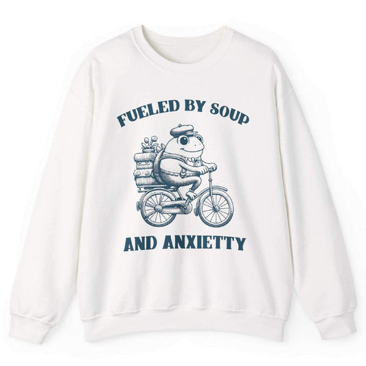 White sweatshirt with frog riding bicycle carrying soup cans and “Fueled by Soup and Anxiety” text – front view, by Shirtcasm
