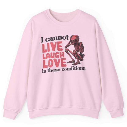 Light pink sweatshirt with distressed skeleton graphic and “I Cannot Live Laugh Love In These Conditions” text – front view, by Shirtcasm